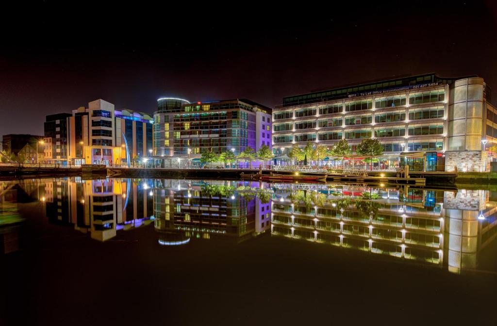 a city lit up at night with a reflection in the water at Clayton Hotel Cork City in Cork