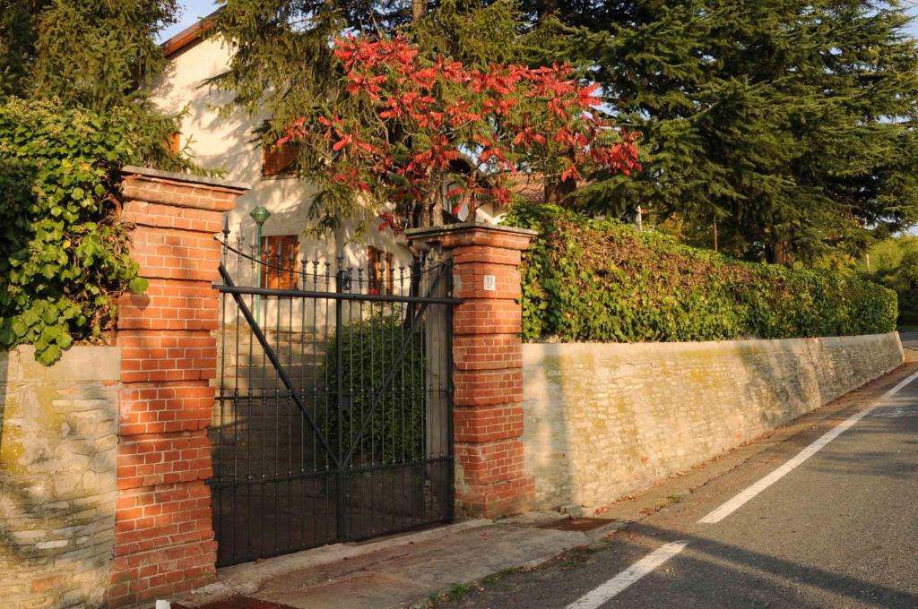 a brick fence with a gate with red flowers on it at B&B Luna di Langa in Alba