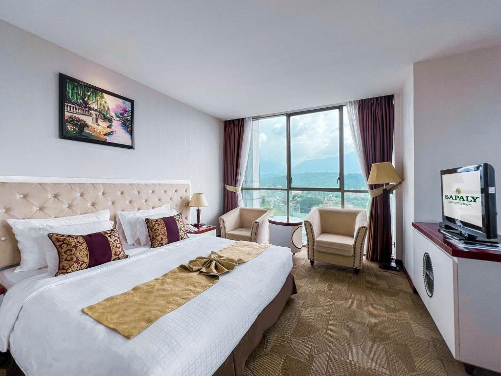 a hotel room with a large bed and a television at Sapaly Lao Cai City Hotel in Lao Cai