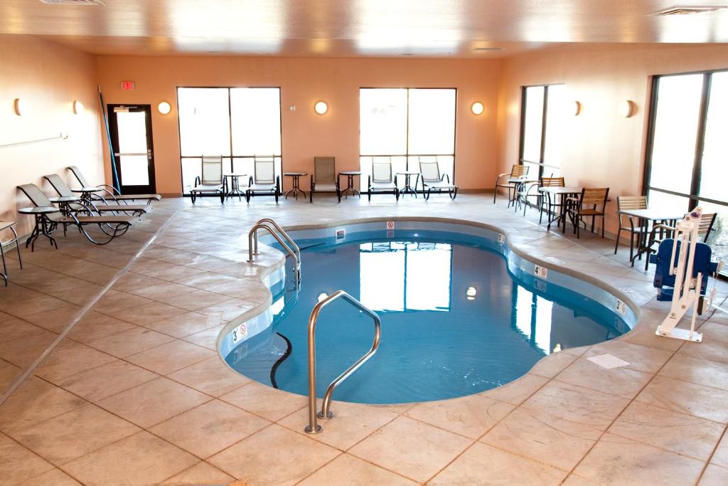 a pool in the middle of a room with tables and chairs at Baymont by Wyndham Rapid City in Rapid City
