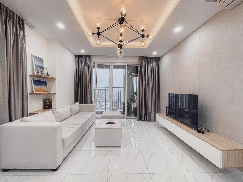 een woonkamer met een witte bank en een tv bij Nhaanhouse Sunrise City in Ho Chi Minh-stad