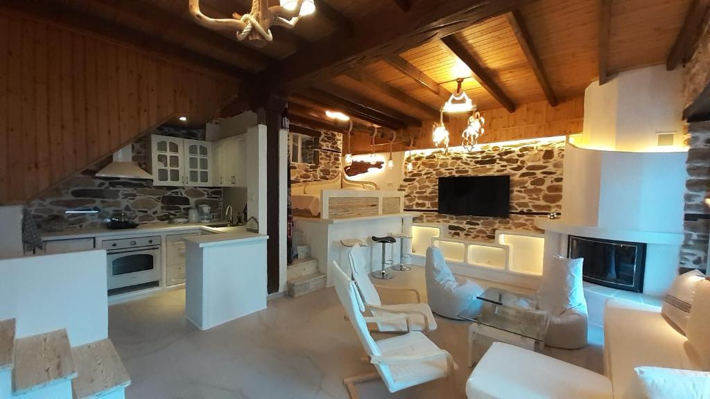 una cucina con mobili bianchi e un muro in pietra di Relax Holistic House a Potamiá
