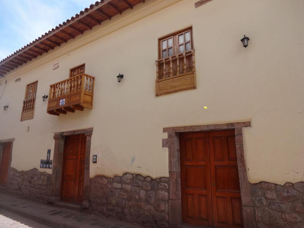 un edificio blanco con puertas y ventanas de madera en OkiDoki Cusco Hostal, en Cusco