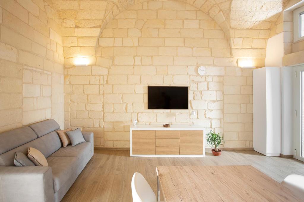 a living room with a couch and a tv on a wall at DonCarlo Suite Relais - Free Parking-parcheggio gratuito in Lecce