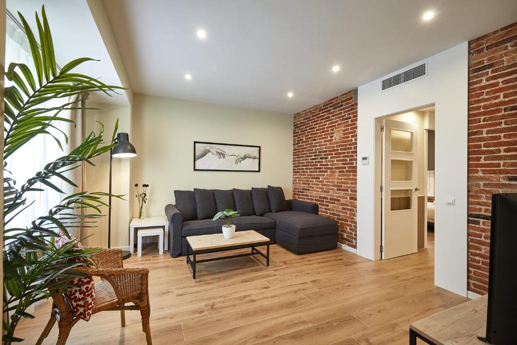 a living room with a couch and a brick wall at BBarcelona Sagrada Familia Flats in Barcelona