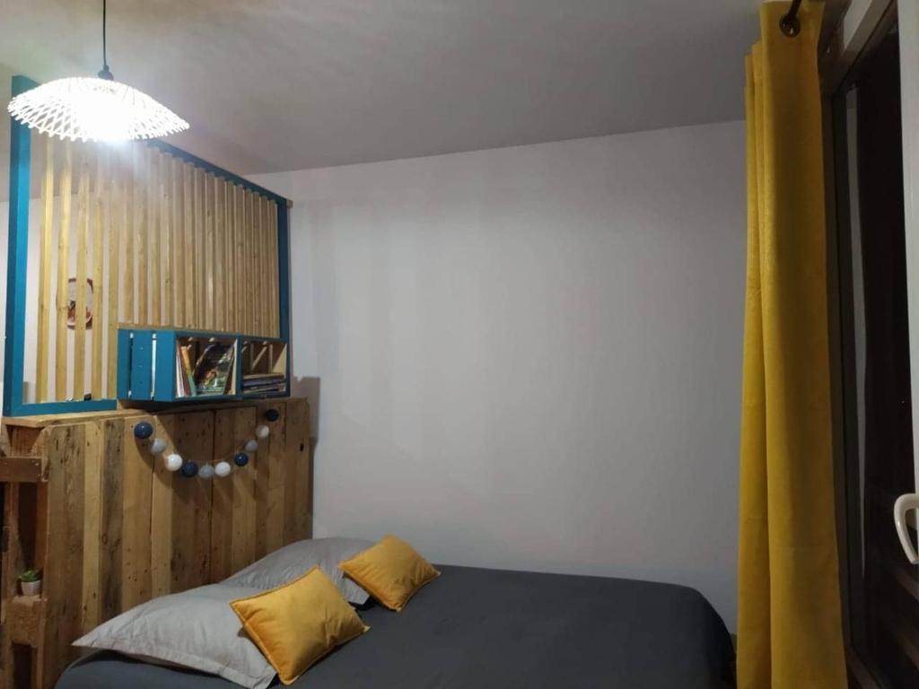 1 dormitorio con 1 cama con 2 almohadas amarillas en Le Bel Horizon, en Le Tampon