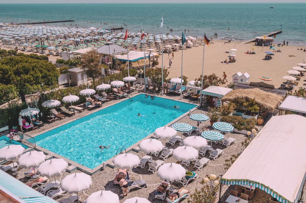 eine Luftansicht auf einen Strand mit Pool und Sonnenschirmen in der Unterkunft Hotel Monaco & Quisisana in Lido di Jesolo