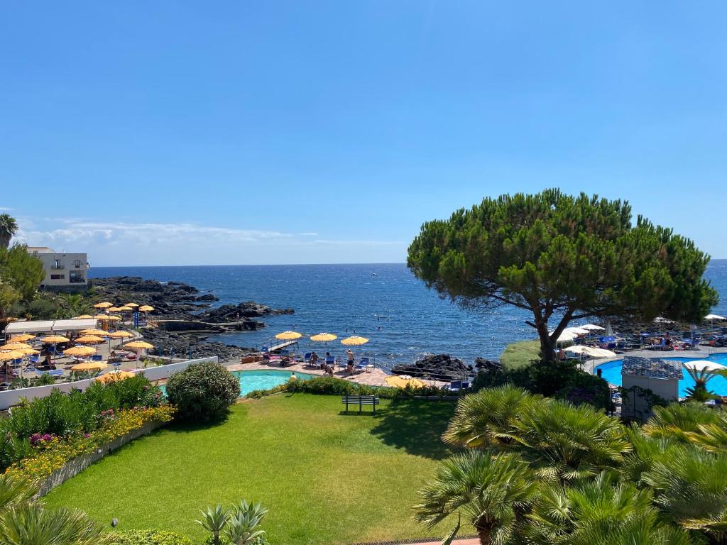 un resort con piscina e spiaggia con ombrelloni di Giardino sul mare a Giardini Naxos