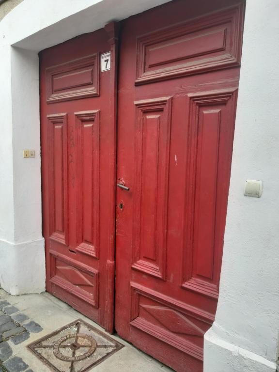 a red door on a white building with a mosaic at APARTMENT POPS 2 in Cluj-Napoca