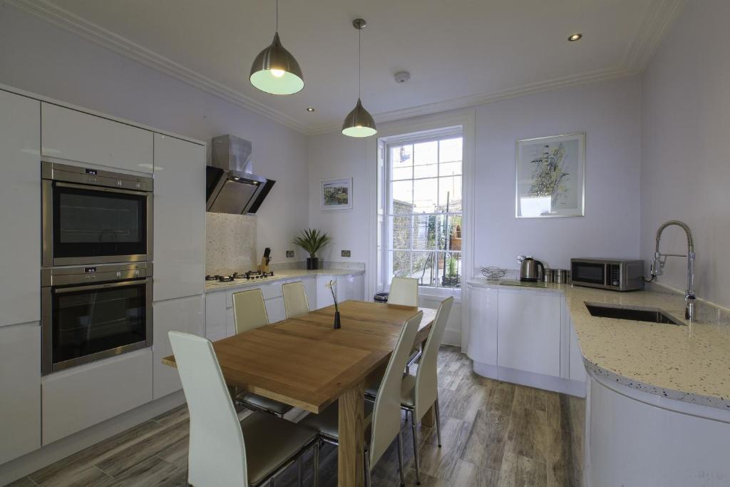 a kitchen with a wooden table and white cabinets at Wellington View: Ground floor apartment with sea views and garden in Kent