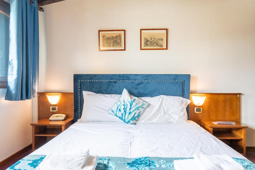 a bedroom with a bed with a blue headboard and two lamps at Hotel Villa Sara in Mestre