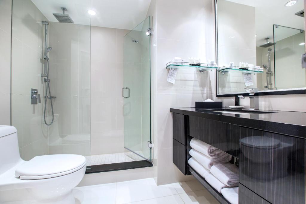 a bathroom with a shower and a toilet and a sink at Granville Island Hotel in Vancouver