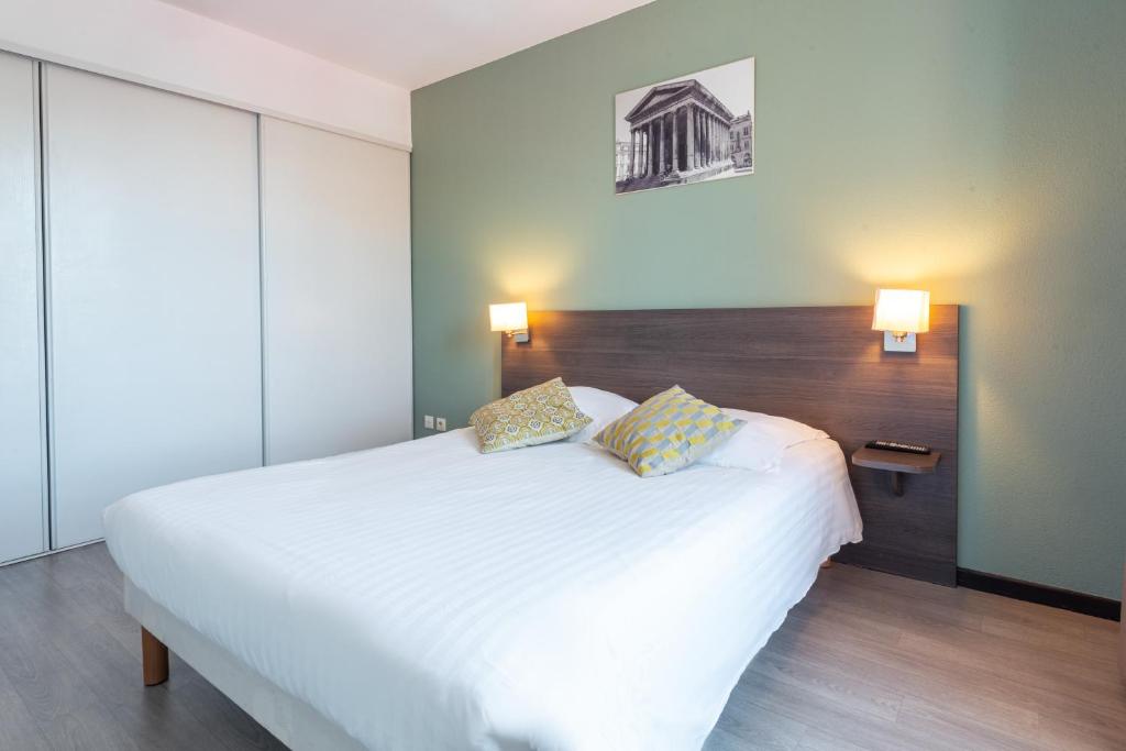 1 dormitorio con 1 cama blanca grande y 2 almohadas en Zenitude Hôtel-Résidences Nîmes Centre en Nimes