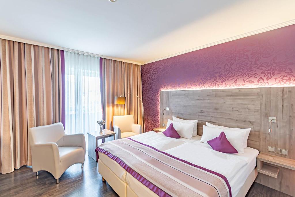 Cette chambre d'hôtel dispose d'un grand lit et d'un mur violet. dans l'établissement Parkhotel Sonnenberg, à Eltville
