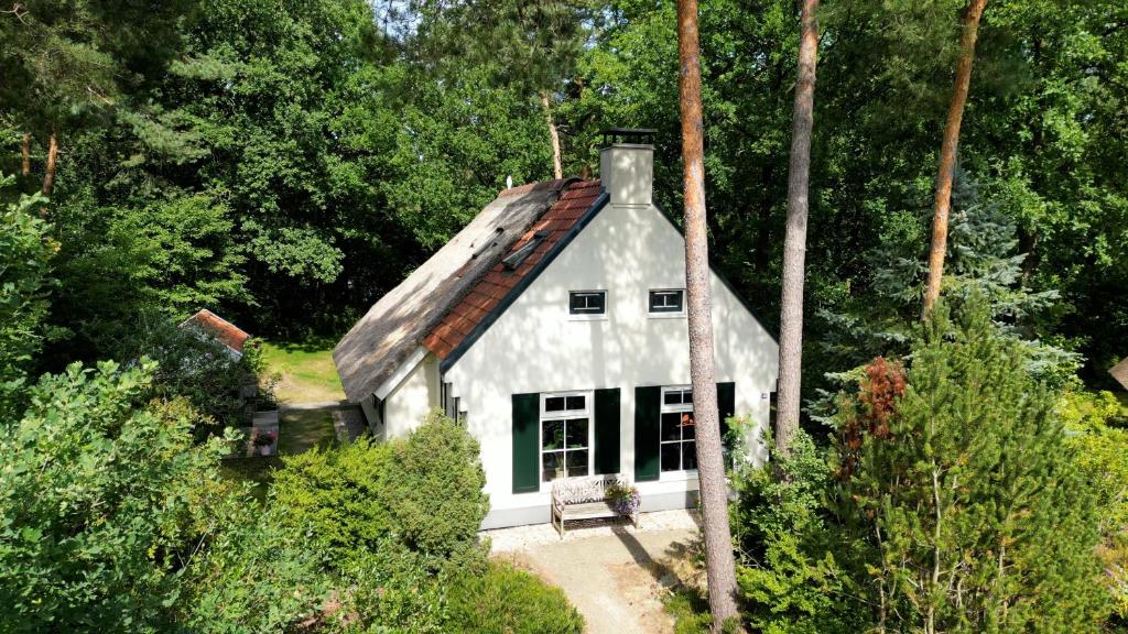 a white house with a roof in the woods at Cottage Hazenhorst - paradijs aan het bos in IJhorst