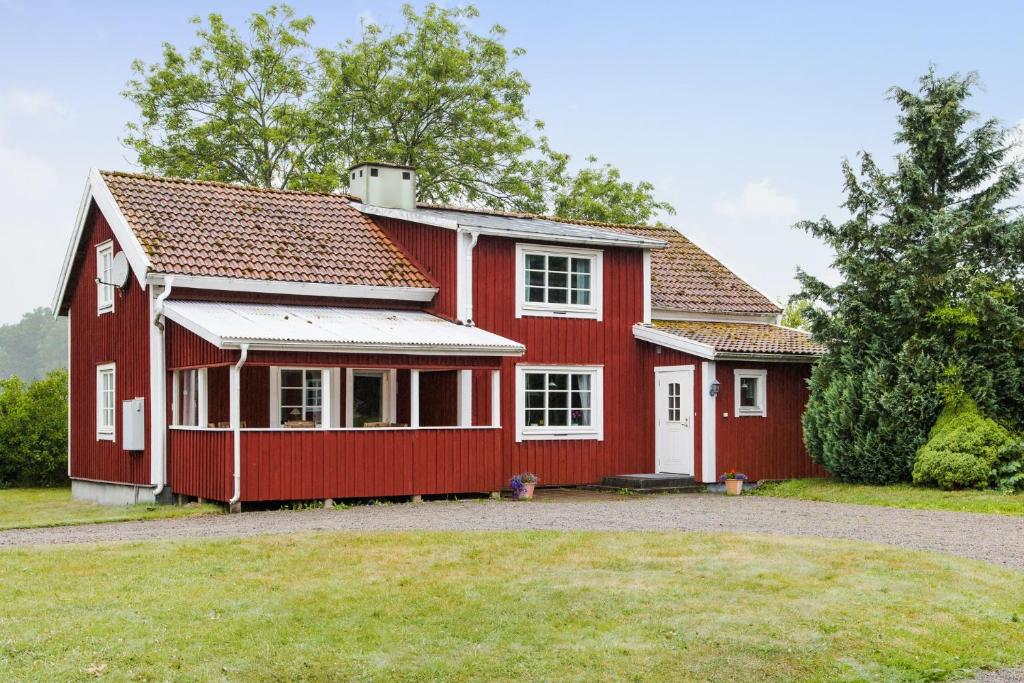 una casa roja con un patio delante en Spacious holiday home in Flattinge, Lagan, 200 m from Lake Flaren, en Vittaryd