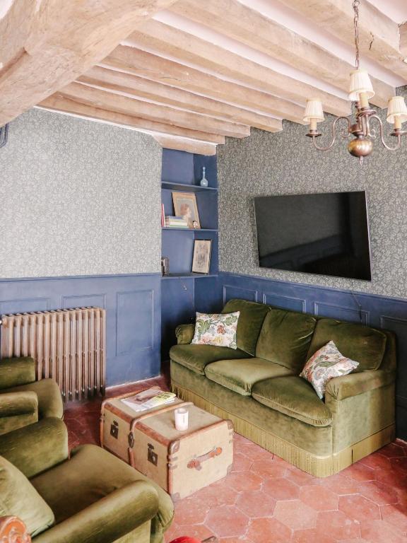 a living room with a couch and a tv at La Maison Pieuse in Villiers-Saint-Benoît