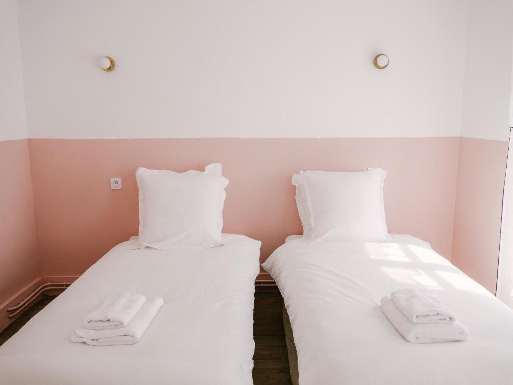 two beds with white sheets and towels on them at La Maison Pieuse in Villiers-Saint-Benoît