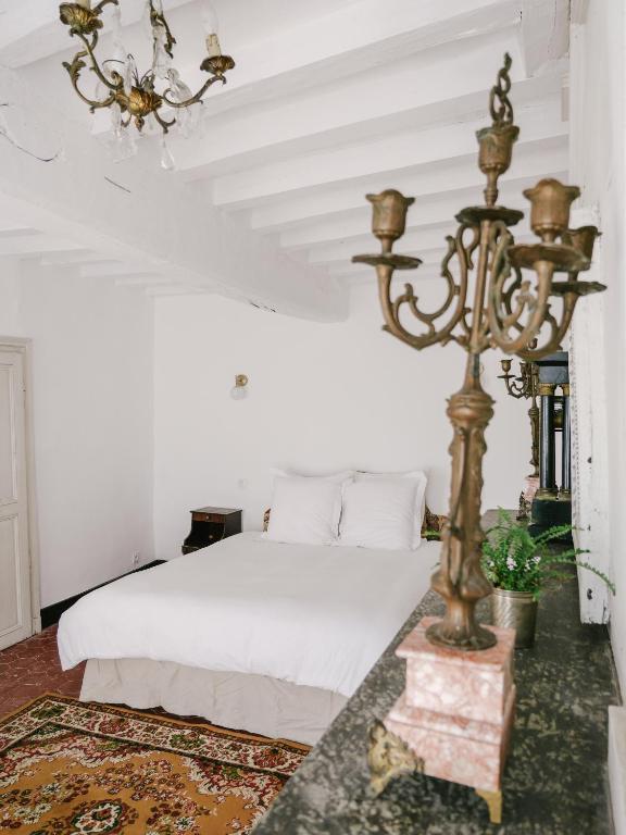 a bedroom with a white bed and a chandelier at La Maison Pieuse in Villiers-Saint-Benoît