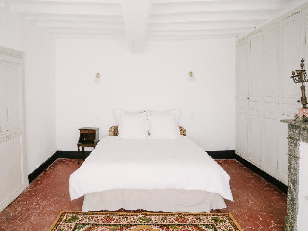 a white bedroom with a white bed and a table at La Maison Pieuse in Villiers-Saint-Benoît