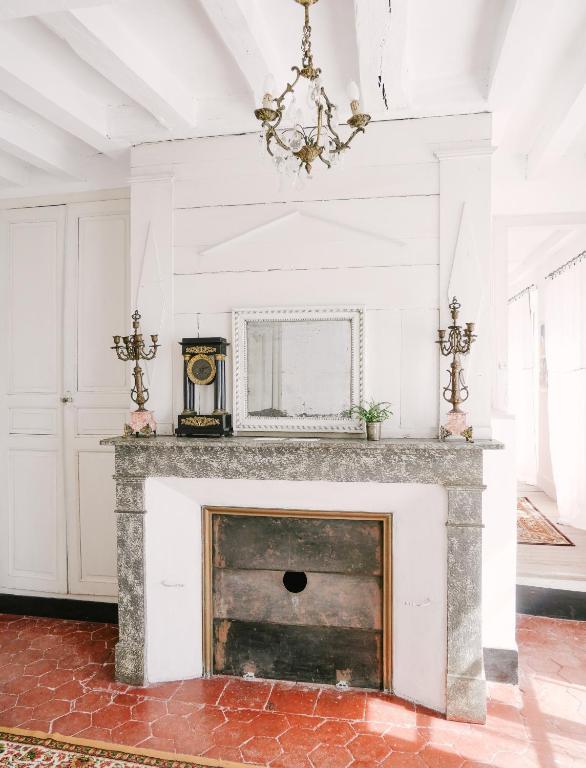 a fireplace in a living room with a chandelier at La Maison Pieuse in Villiers-Saint-Benoît
