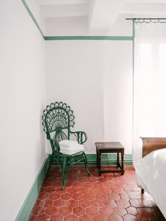 a green chair sitting in a room with a table at La Maison Pieuse in Villiers-Saint-Benoît