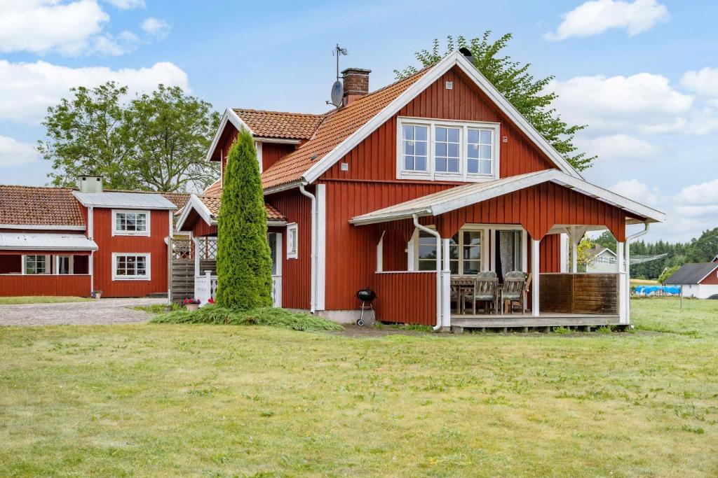 ein rotes Haus mit einem großen Hof davor in der Unterkunft Lovely holiday home in the village of Flattinge, with a view of lake Flaren in Vittaryd