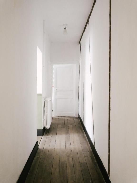 a hallway with a white door and a wooden floor at La Maison Pieuse in Villiers-Saint-Benoît