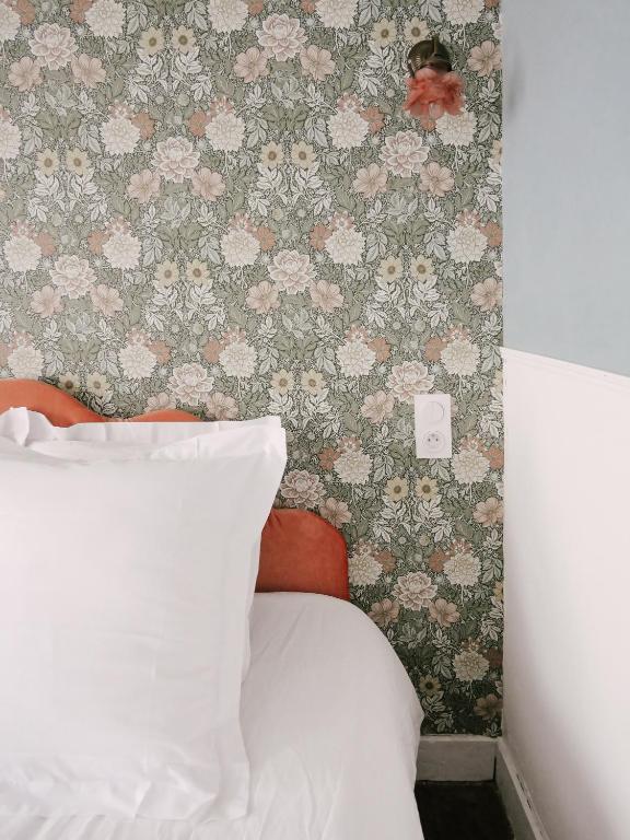 a bed with a white pillow and a wall with flowers at La Maison Pieuse in Villiers-Saint-Benoît