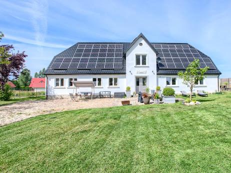 a white house with solar panels on the roof at Dom nad morzem Ludwikowo in Skrzeszewo