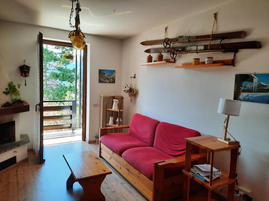 Una sala de estar con un sofá rojo y una ventana. en Finestra sul Cermis, en Carano