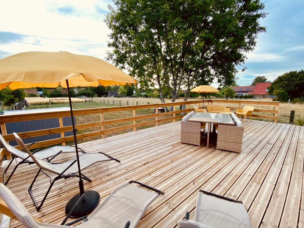 a deck with a table and chairs and an umbrella at Aux 3 Noyers in Croissy-sur-Celle