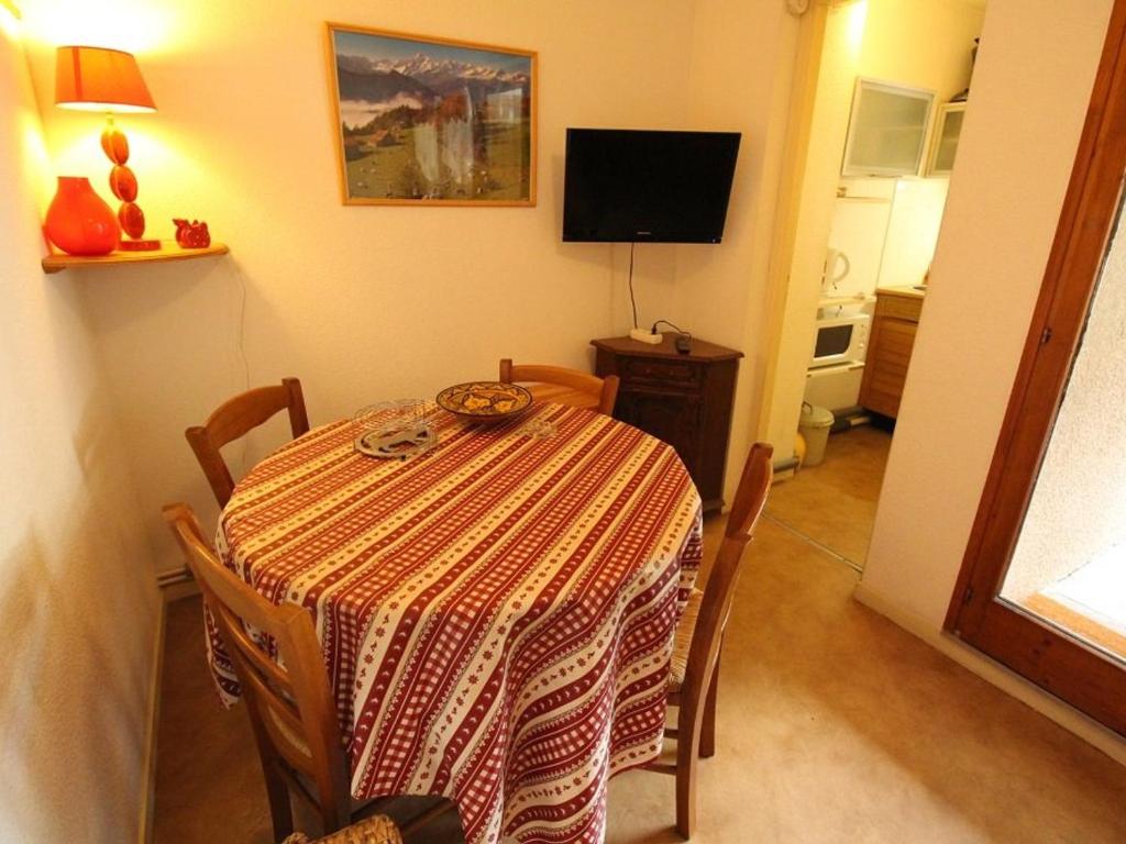 a dining room with a table with chairs and a television at Studio Bagnères-de-Luchon, 1 pièce, 4 personnes - FR-1-313-130 in Luchon