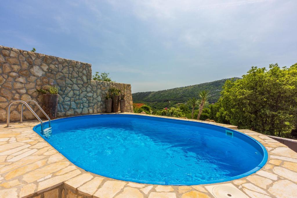 une grande piscine bleue avec un mur en pierre dans l'établissement Villa Romantic, à Bribir
