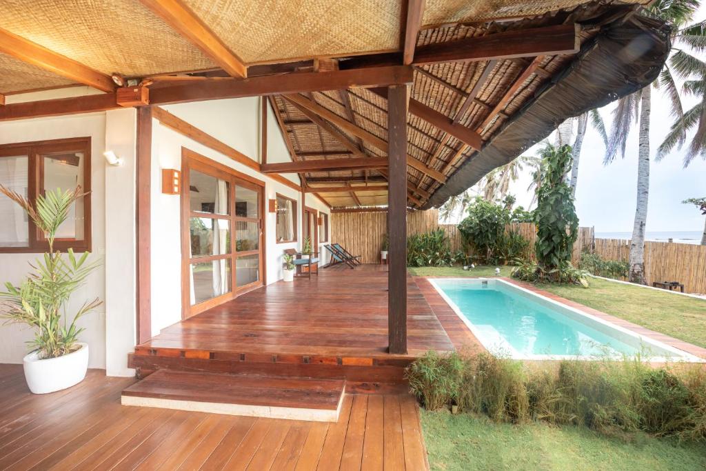 a house with a wooden deck and a swimming pool at Rare Beachfront Villa - 2BR - 6 Pax Private Pool on Tuason Surf Spot in General Luna