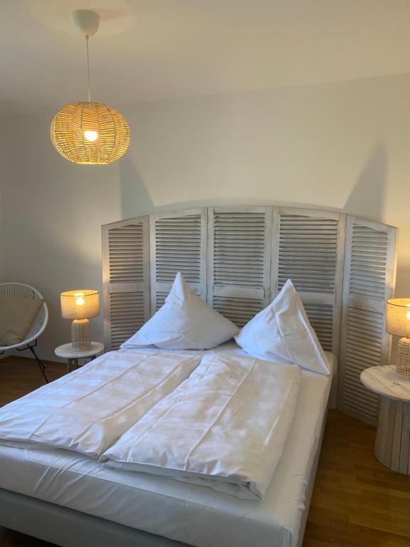 Una cama con sábanas blancas y almohadas en un dormitorio en Chiemsee Ferienwohnung Gartenblick en Prien am Chiemsee