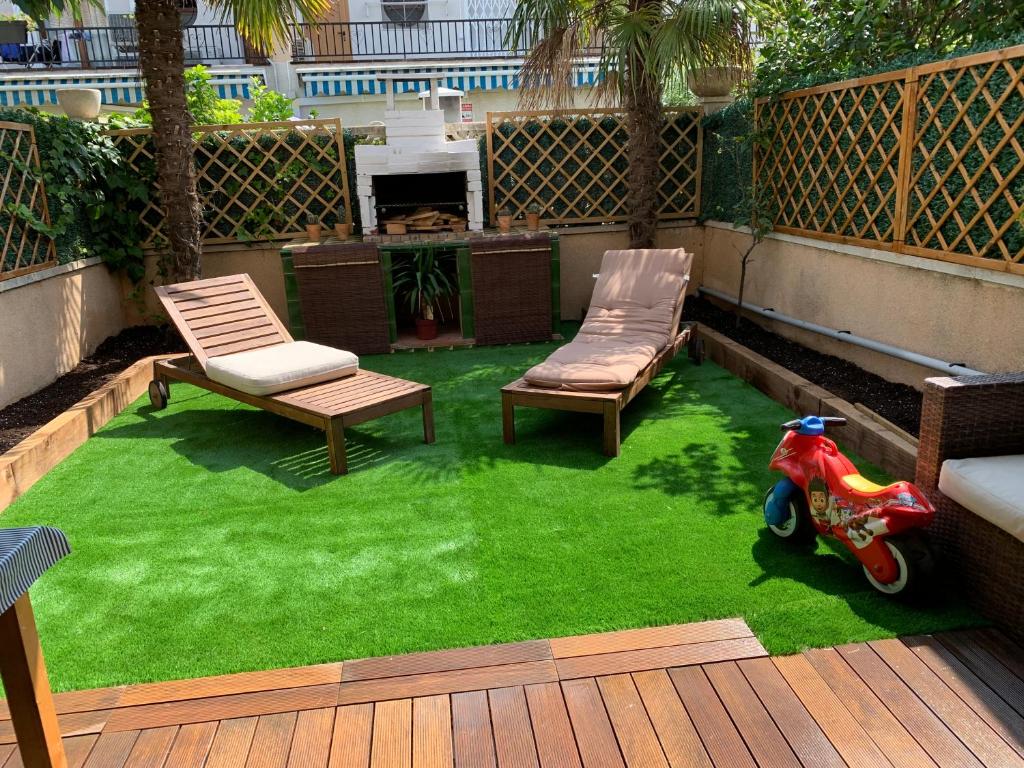 a yard with a lawn with two chairs and a scooter at Casa de playa in Tarragona
