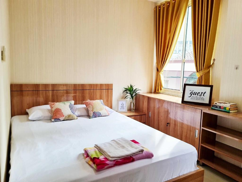 um quarto com uma cama com lençóis brancos e uma janela em 37 Guesthouse em Jakarta