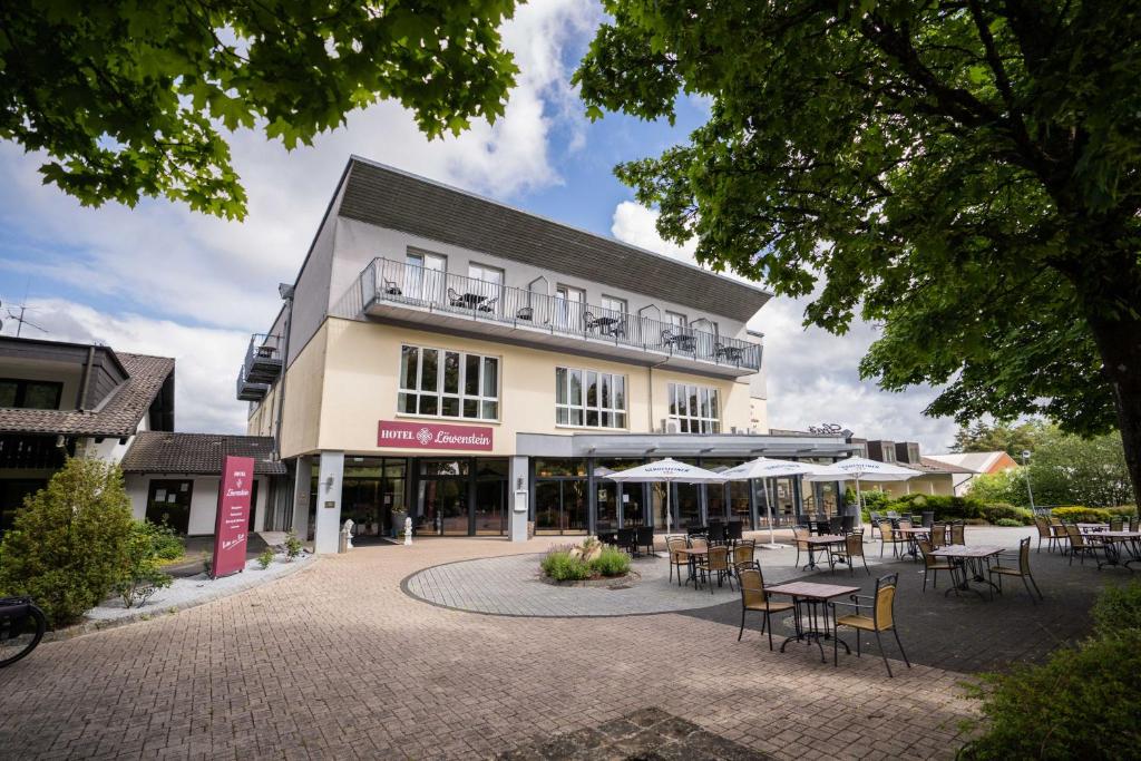 un edificio con mesas y sillas delante de él en Hotel Löwenstein, en Gerolstein