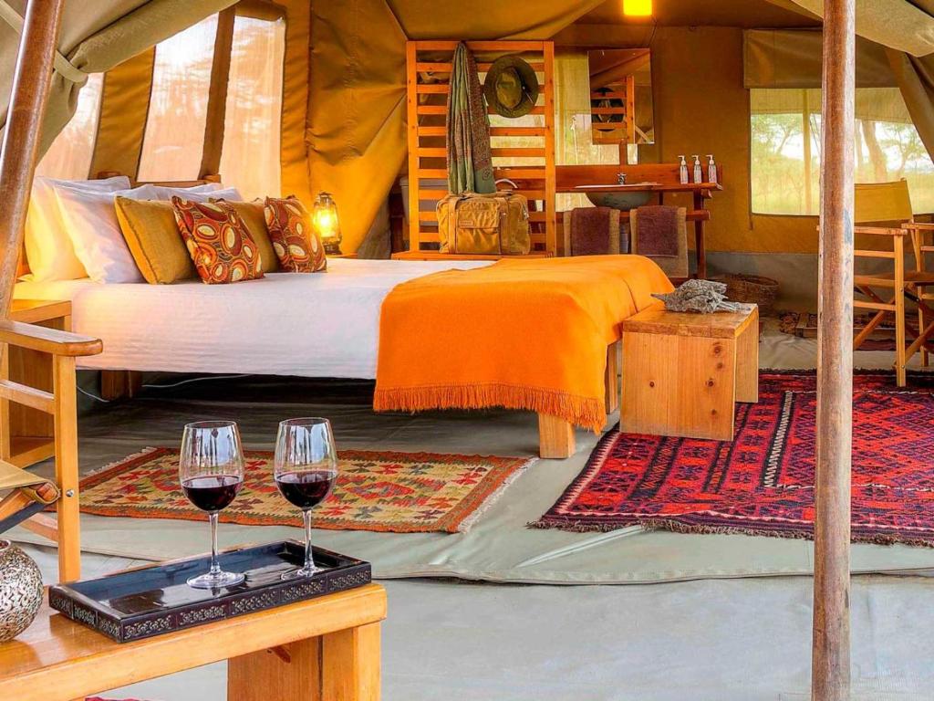 een slaapkamer met een bed en twee glazen wijn bij Kandili Camp in Musiara Campsite