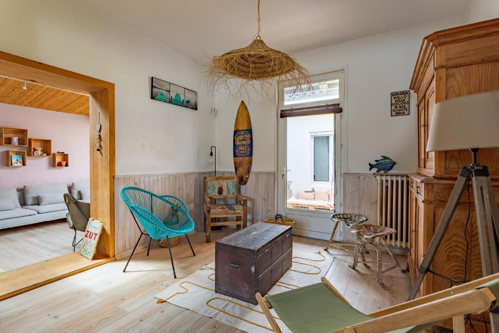 ein Wohnzimmer mit einem Tisch und einem Surfbrett an der Wand in der Unterkunft Villa à 2 pas de la plage in Arcachon