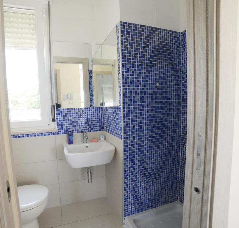 La salle de bains est pourvue de carrelage bleu, d'un lavabo et de toilettes. dans l'établissement VIRGOLA ZERO HOLIDAY BEACH, à Porto Potenza Picena