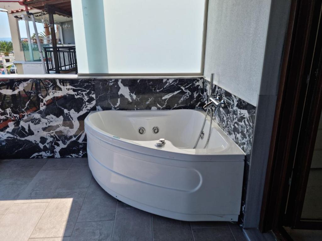 - białą wannę w pokoju ze ścianą w obiekcie Lux Suite Sea Front Avra w mieście Pefkochori