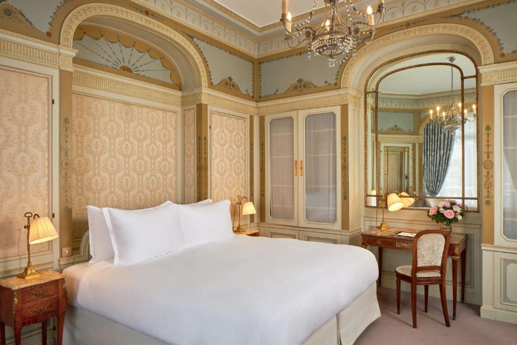 a bedroom with a large white bed and a mirror at Hôtel Raphael in Paris