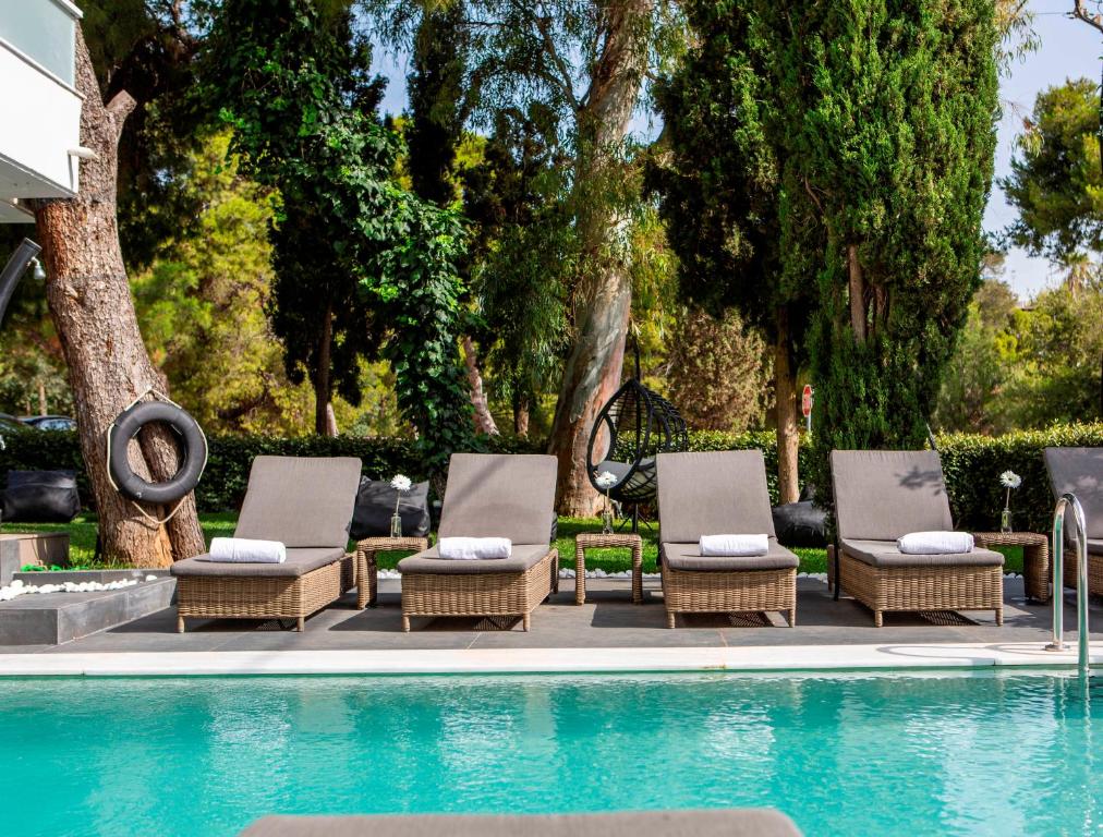 - un groupe de chaises assises à côté de la piscine dans l'établissement Athenian Riviera Hotel& Suites, à Athènes