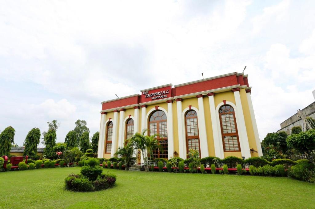 un bâtiment avec une pelouse devant lui dans l'établissement The Imperial Kushinagar, à Kushinagar