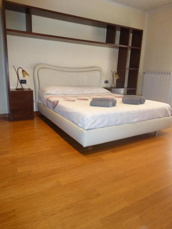 Appartamento yestravel noale في نوالي: غرفة نوم بسرير أبيض مع أرضية خشبية