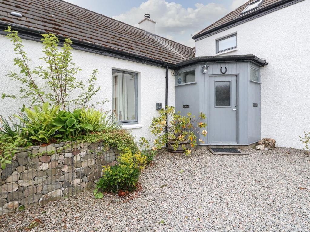 a white house with a door and a stone wall at Cedar in Newtonmore