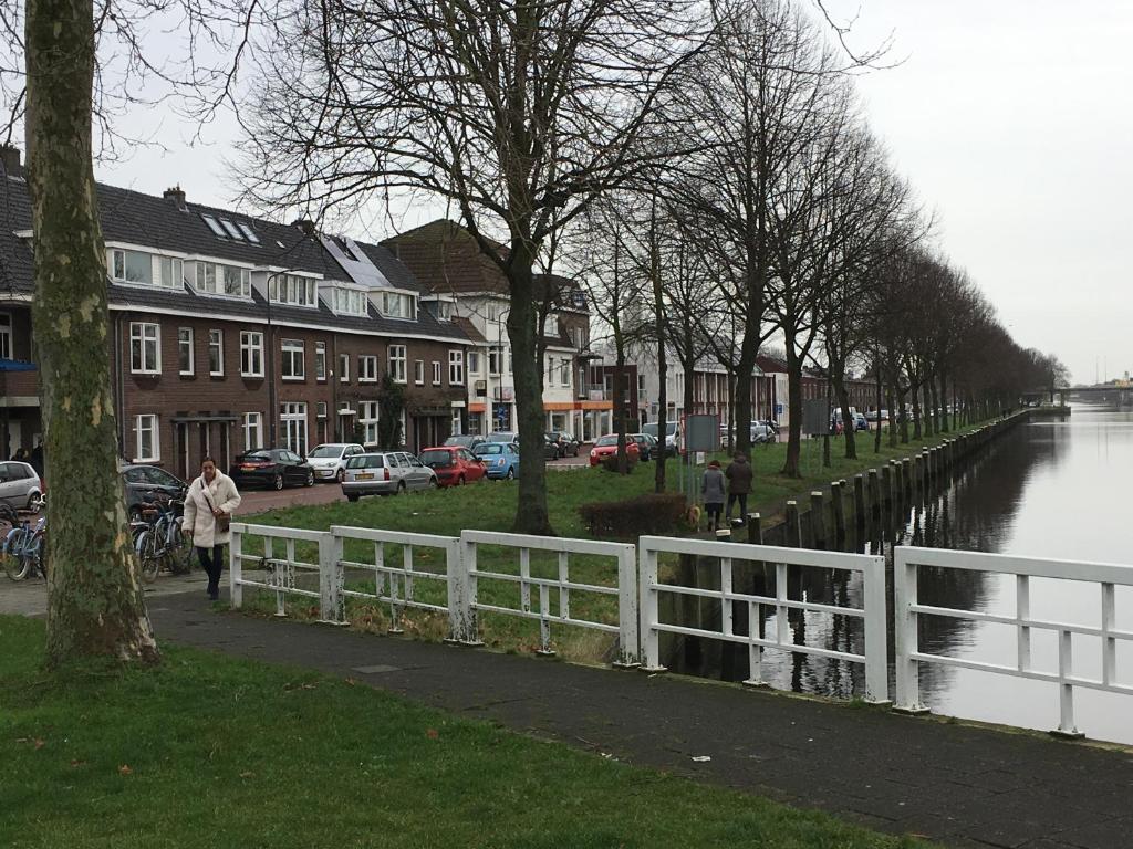 una mujer caminando por una acera junto a una cerca blanca en Appartement aan De Zuid-Willemsvaart Den Bosch, en De Pettelaar