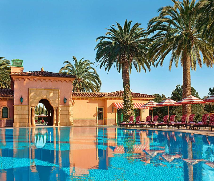 a swimming pool with palm trees and a building at Fairmont Grand Del Mar in San Diego